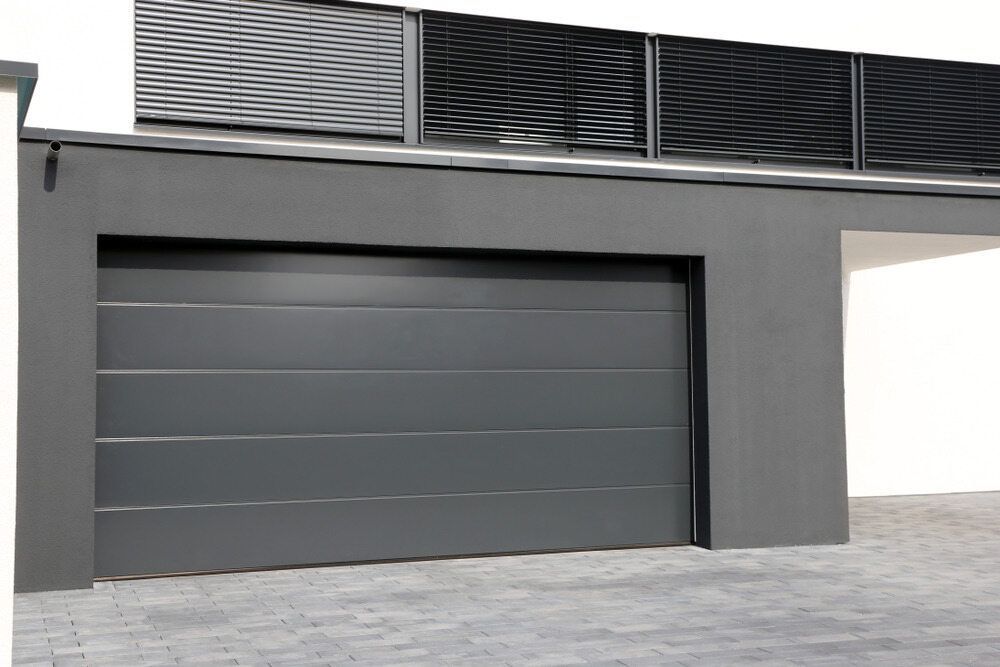 A Gray Garage Door With a White Building in the Background — The Roller Door Man NQ In Atherton, QLD