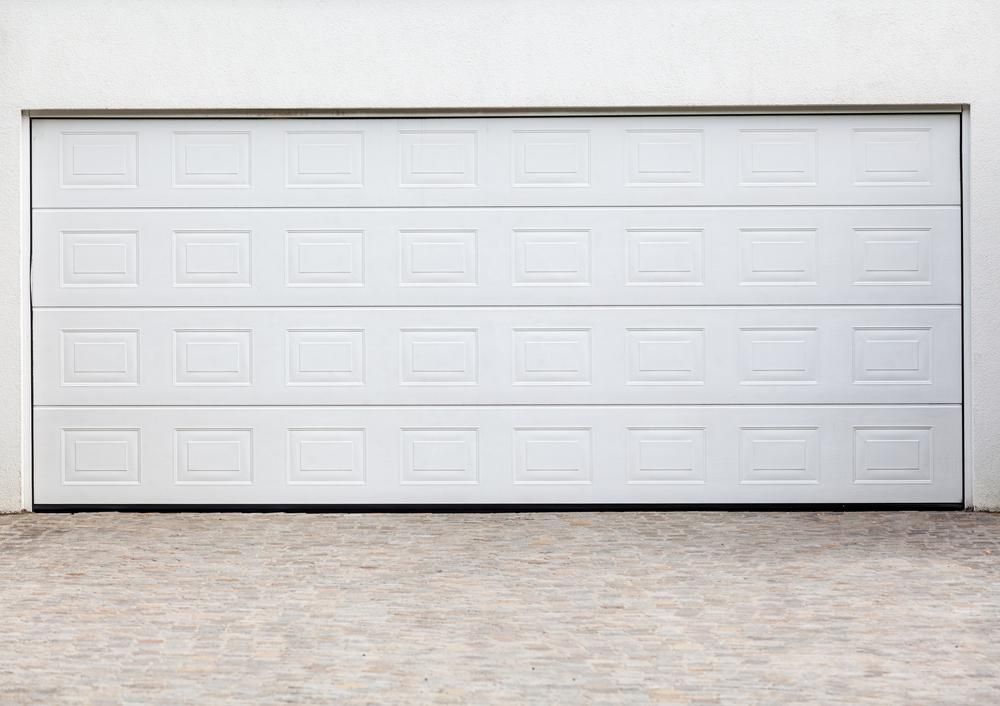 A White Garage Door Is Open On A Brick Driveway — The Roller Door Man NQ In Portsmith, QLD