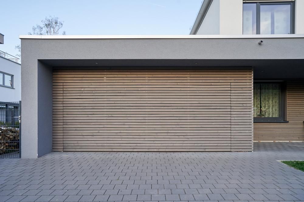 A Modern House With A Wooden Garage Door And A Brick Driveway — The Roller Door Man NQ In Portsmith, QLD