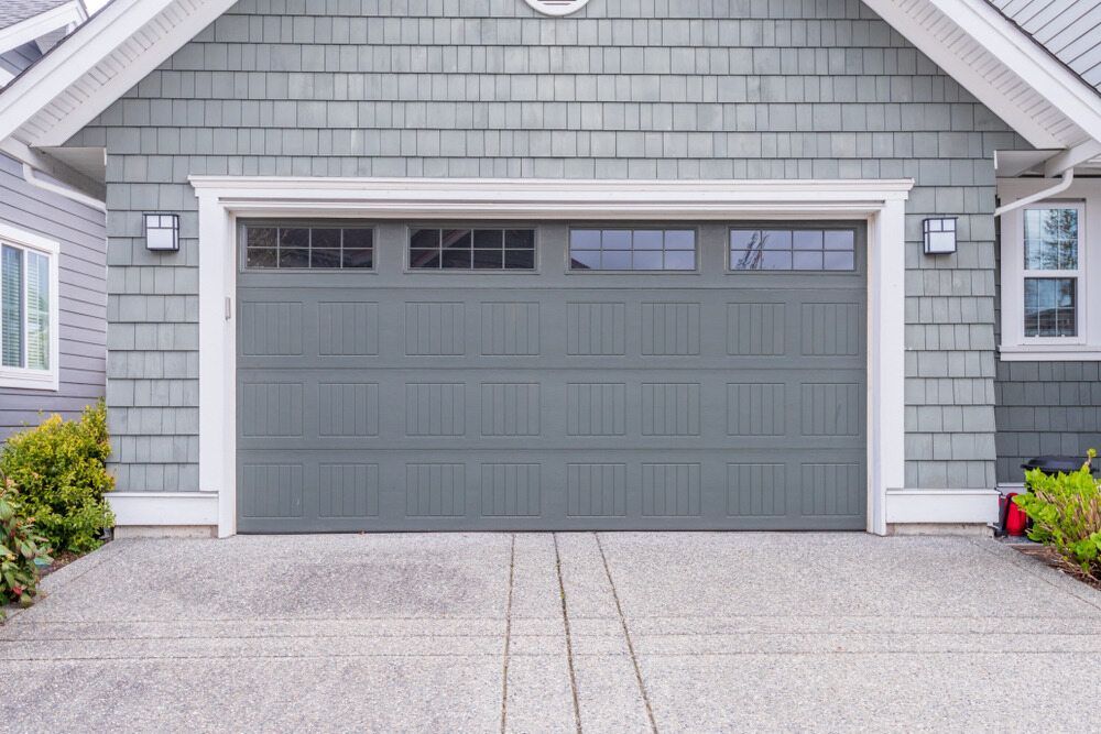 A Gray Garage Door is Sitting in Front of a Gray House — The Roller Door Man NQ In Atherton, QLD