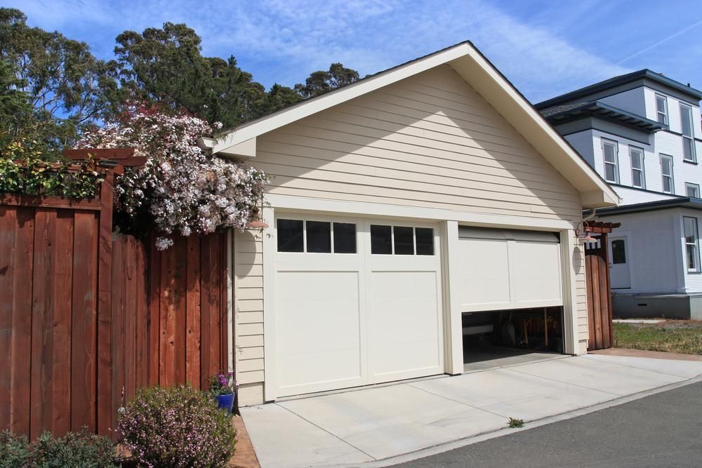 A White Garage With A Wooden Fence In Front Of It — The Roller Door Man NQ In Portsmith, QLD