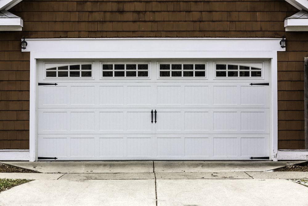 A White Garage Door is on the Side of a House — The Roller Door Man NQ In Redlynch, QLD