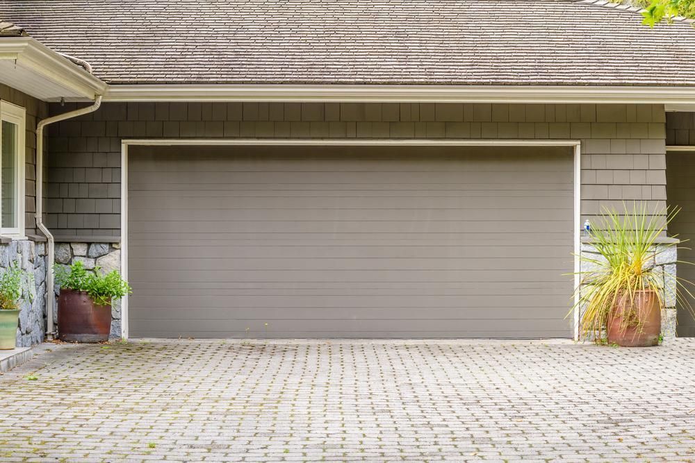 A Garage Door Is Open In Front Of A House With A Brick Driveway — The Roller Door Man NQ In Cairns, QLD