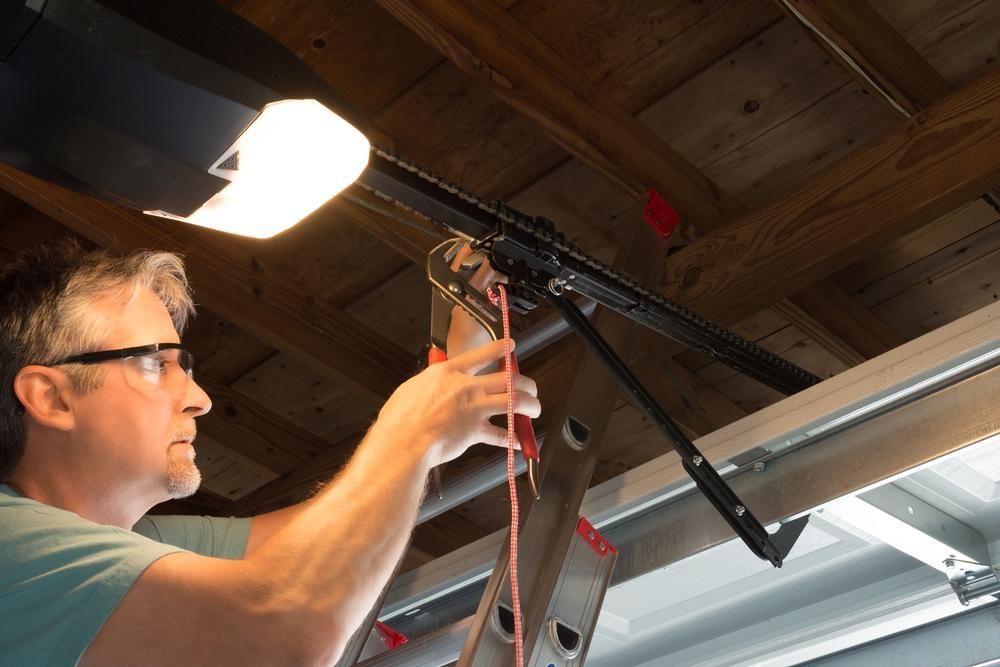 A Man Is Working On A Garage Door Opener In A Garage — The Roller Door Man NQ In Portsmith, QLD