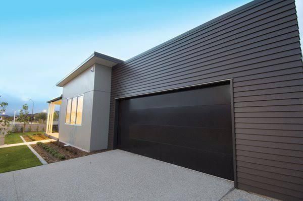 A Large Garage Door Is Sitting In Front Of A House — The Roller Door Man NQ In Tablelands, QLD