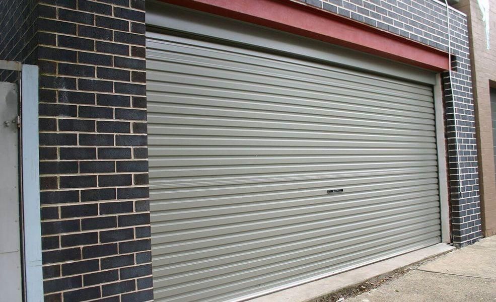 A Garage Door With A Brick Wall Behind It — The Roller Door Man NQ In Portsmith, QLD
