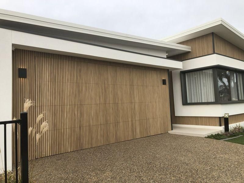A Modern House With A Large Wooden Garage Door — The Roller Door Man NQ In Portsmith, QLD