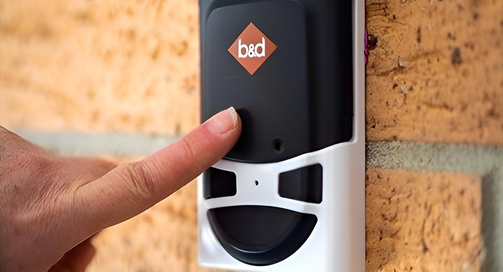 A Person Is Pressing A Button On A Device On A Brick Wall — The Roller Door Man NQ In Portsmith, QLD