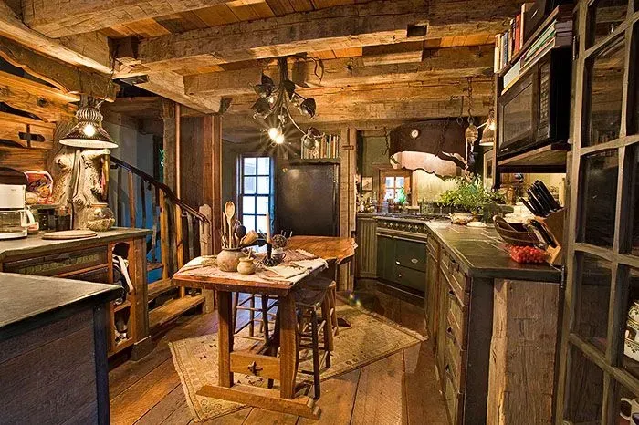 Rustic kitchen with wooden beams, dark cabinets, and spiral staircase.