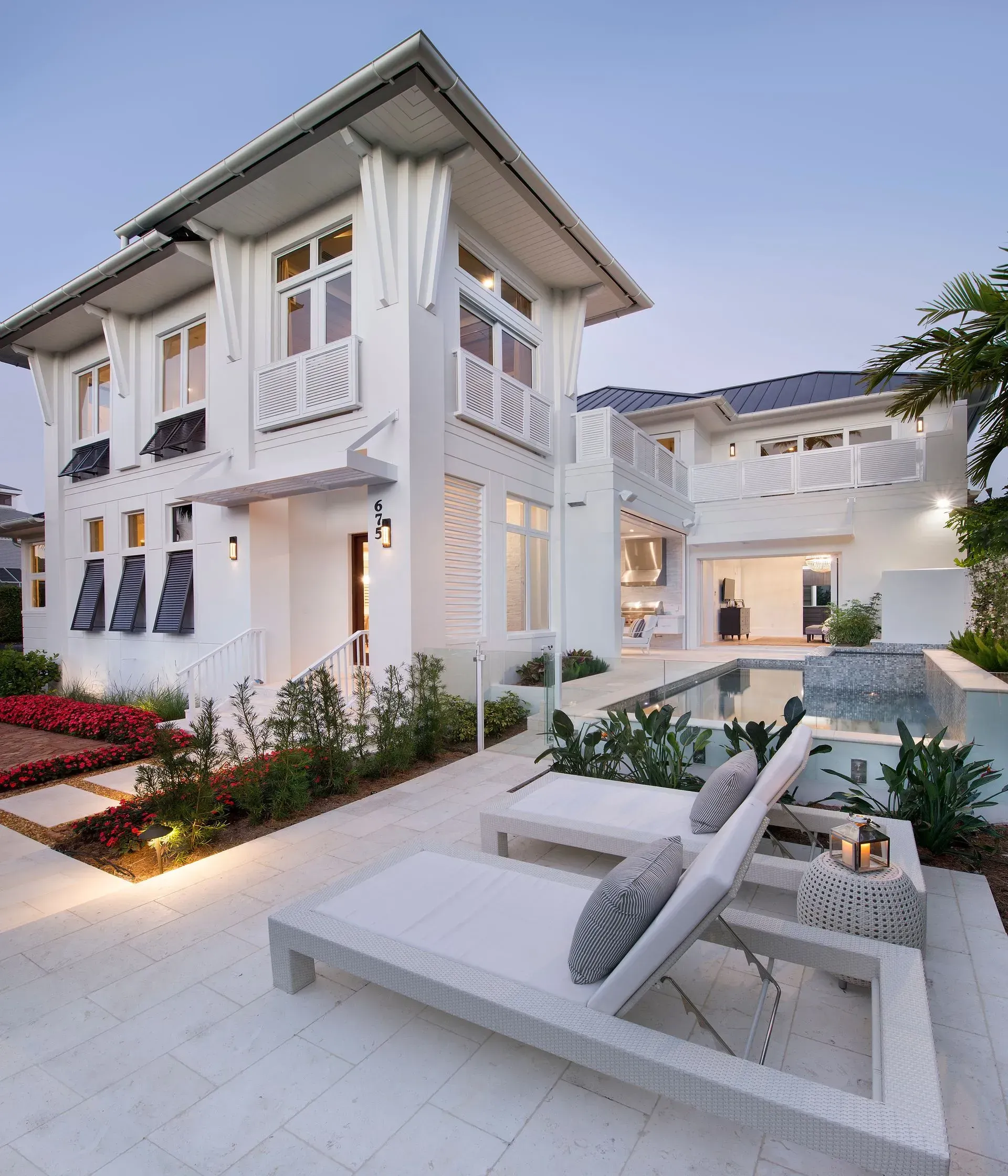 White two-story house with pool, lounge chairs, and landscaping.