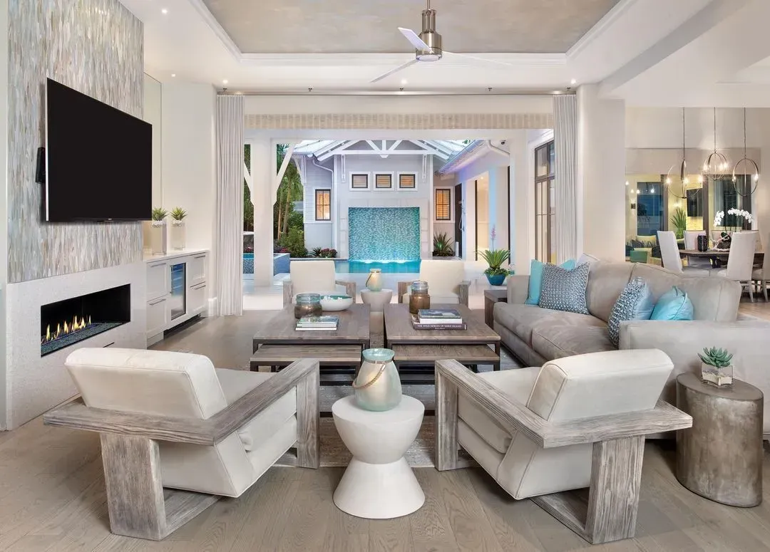 Bright living room with white walls, blue accents, staircase, and a view to dining area.