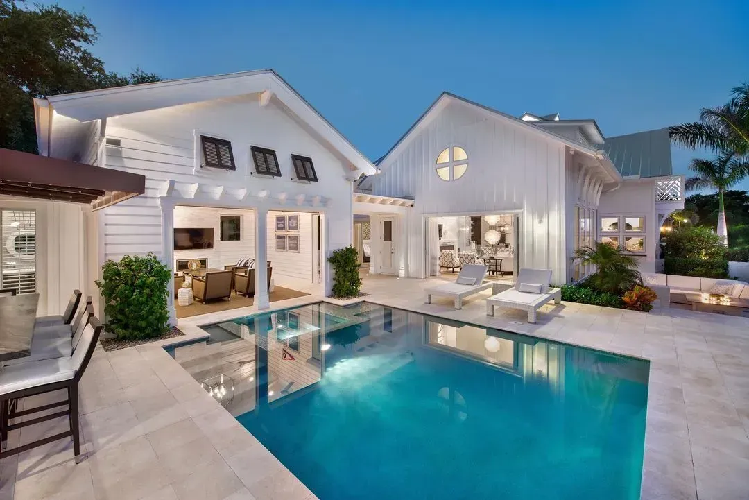White coastal home with a pool at dusk.