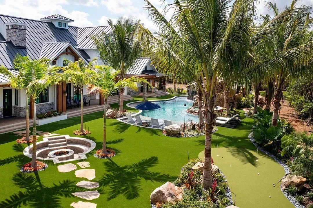 Luxurious home with pool, palm trees, and manicured lawn.