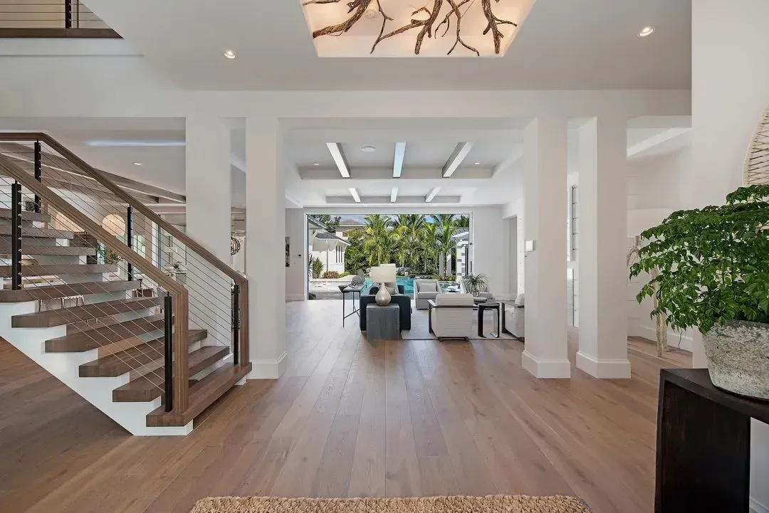Spacious entry hall with wood floors, staircase, and view to outdoor patio.