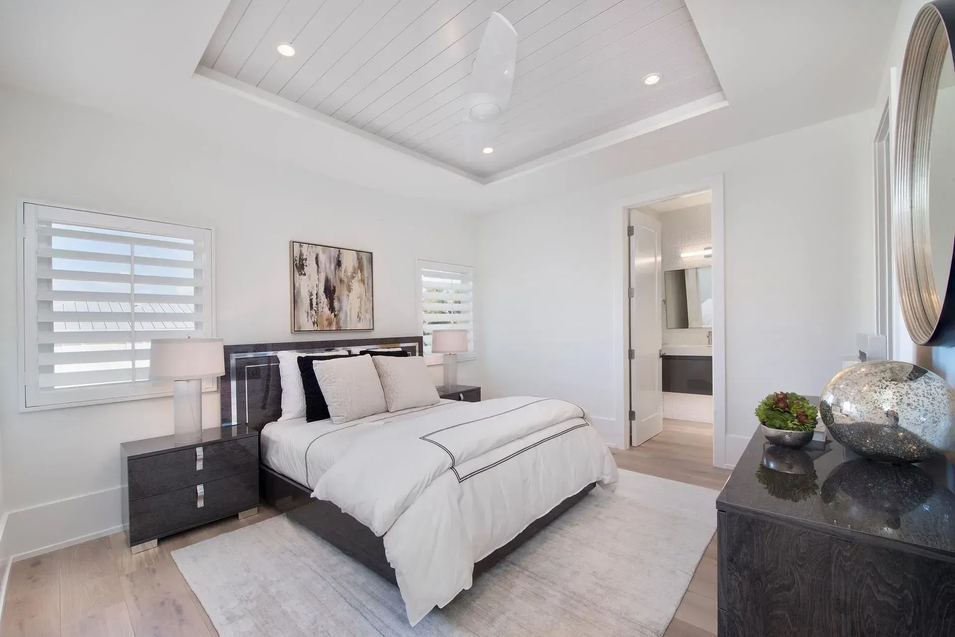 Bedroom with white walls, bed, dresser, and a door leading to a bathroom.