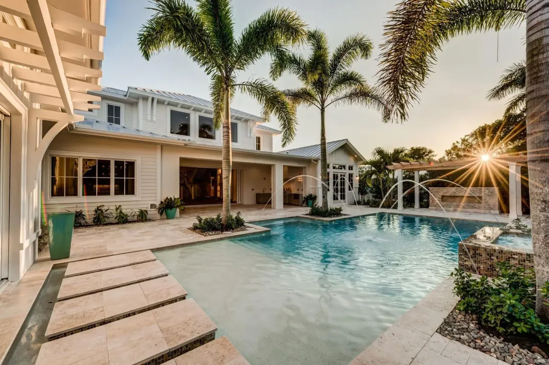 Luxury home with pool, palm trees, and sunset.