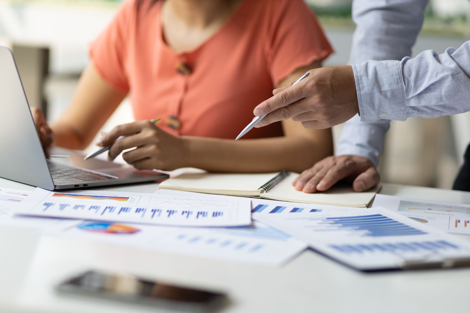 People pointing at charts and graphs during a business meeting at a desk