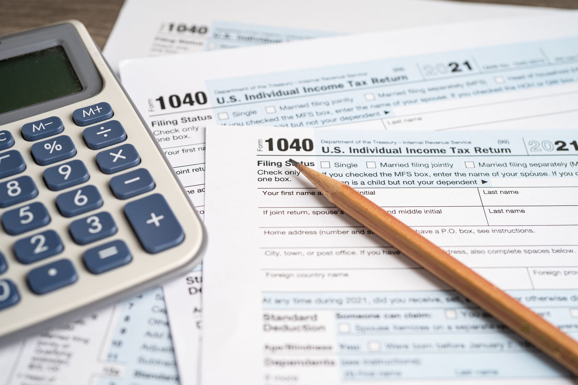 Calculator, pencil, and IRS 1040 tax form on a desk