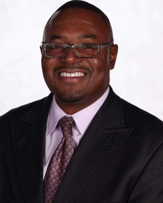 A man in a suit and tie is smiling for the camera