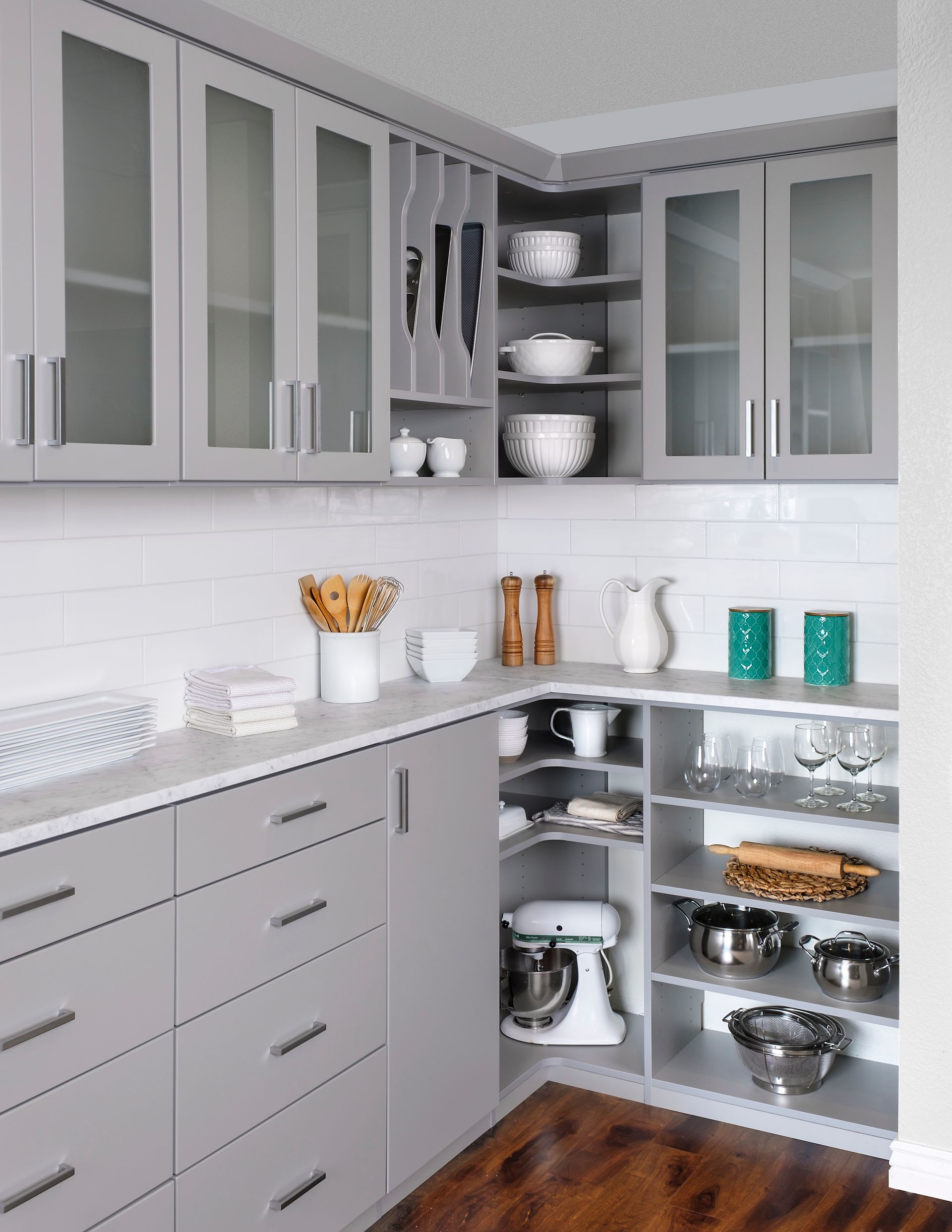 A well-organized walk-in closet with teal cabinetry and white shelving. Clothes hang, and decorative items are on display.