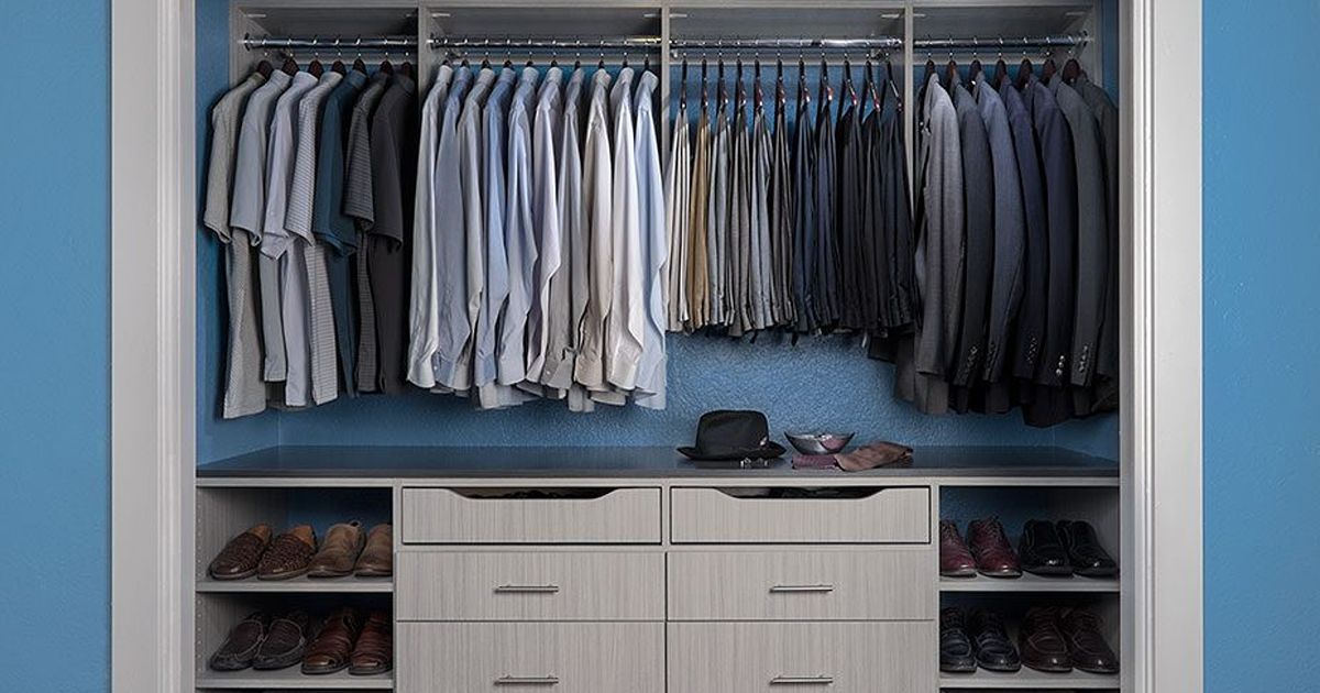 Walk-in closet with hanging clothes in shades of blue and gray, drawers, and shoe storage.