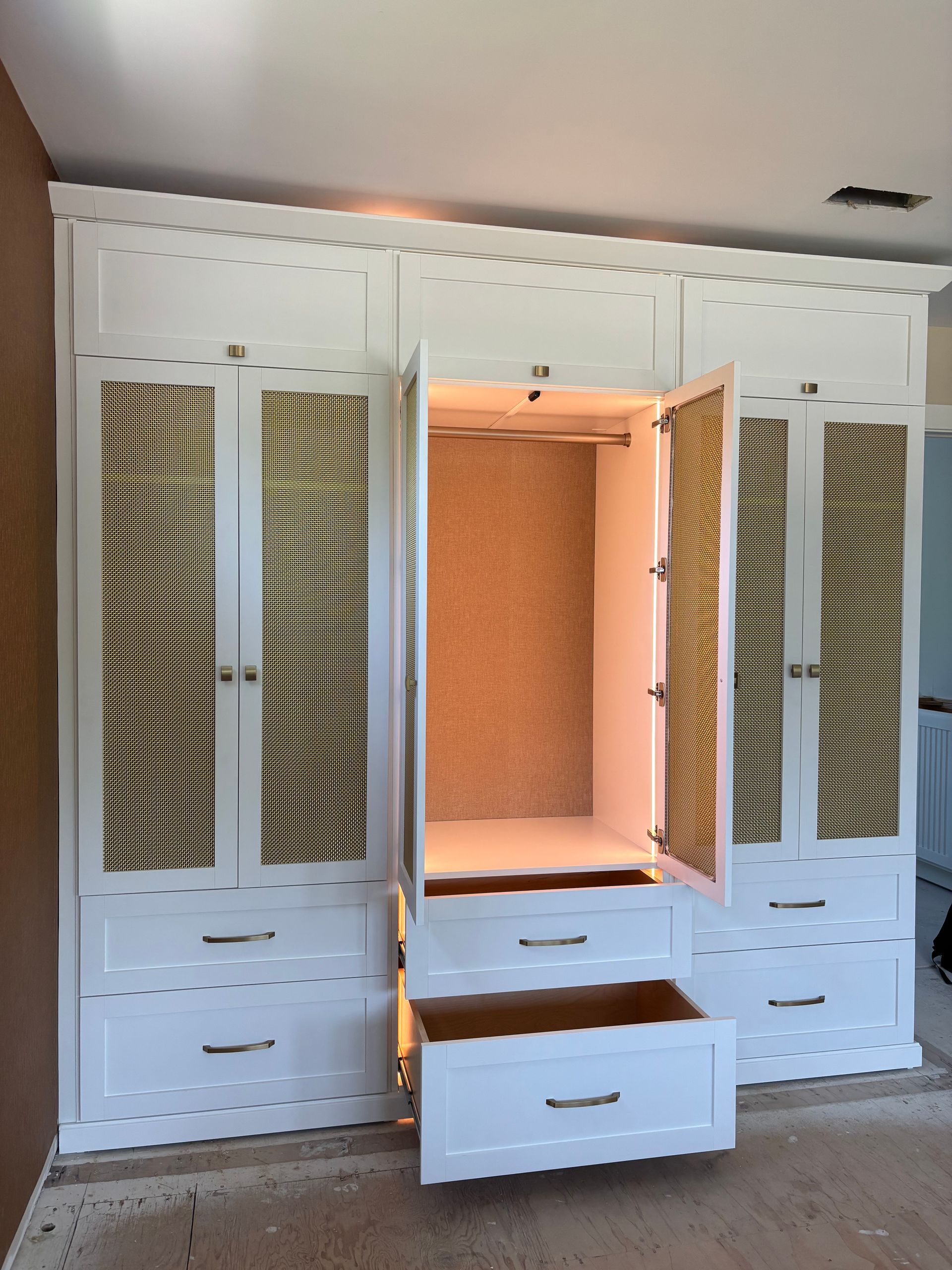 Built-in white closet with open central shelving and a pulled-out drawer in a bedroom.