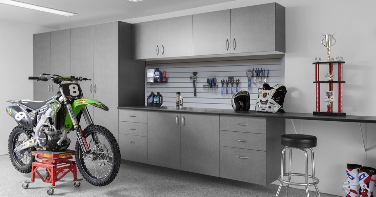 Garage with a motorcycle, cabinets, workbench, and tools.