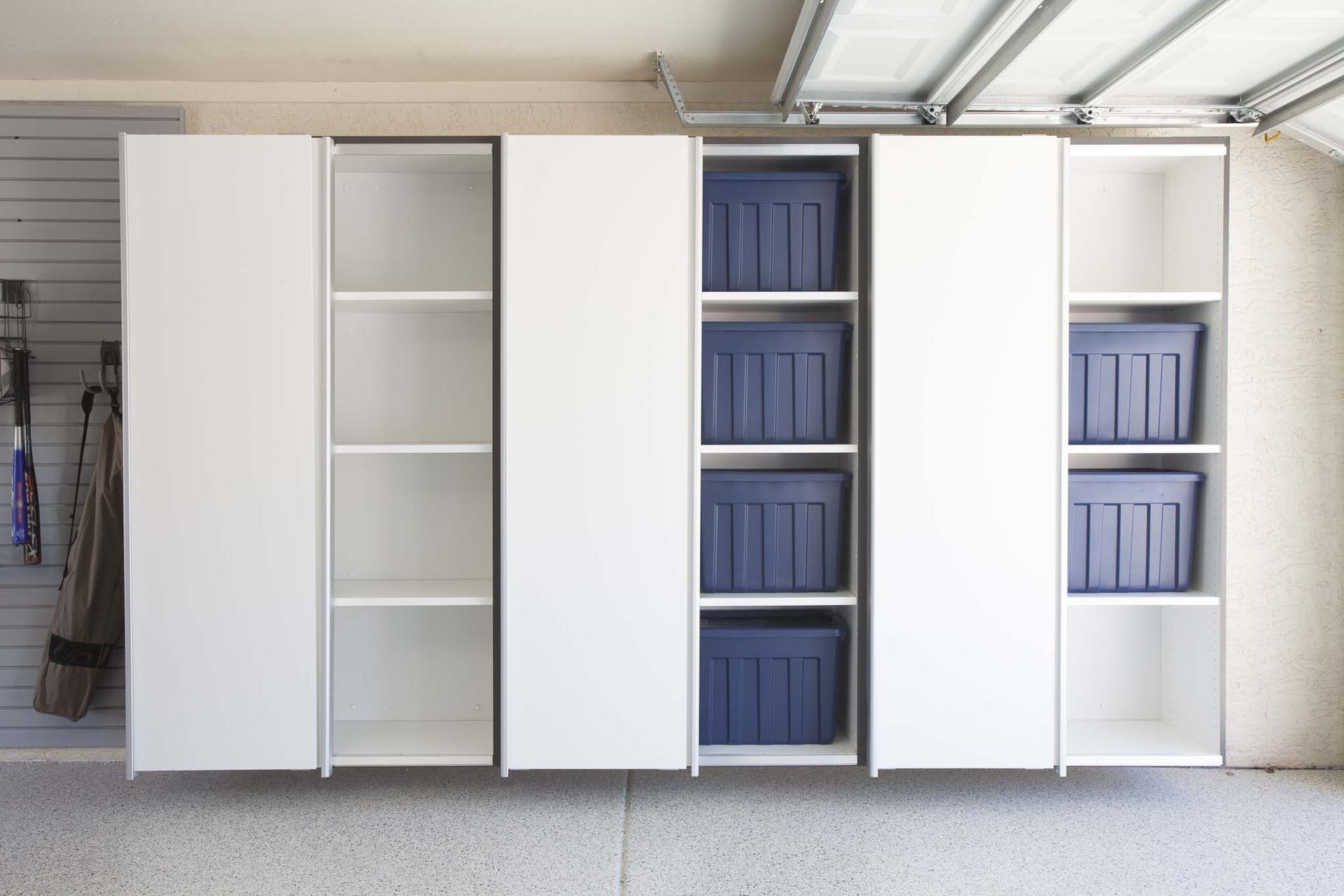 A reach in closet with gray shelving, drawers, and hanging rods for clothes. Clothing is organized by color.
