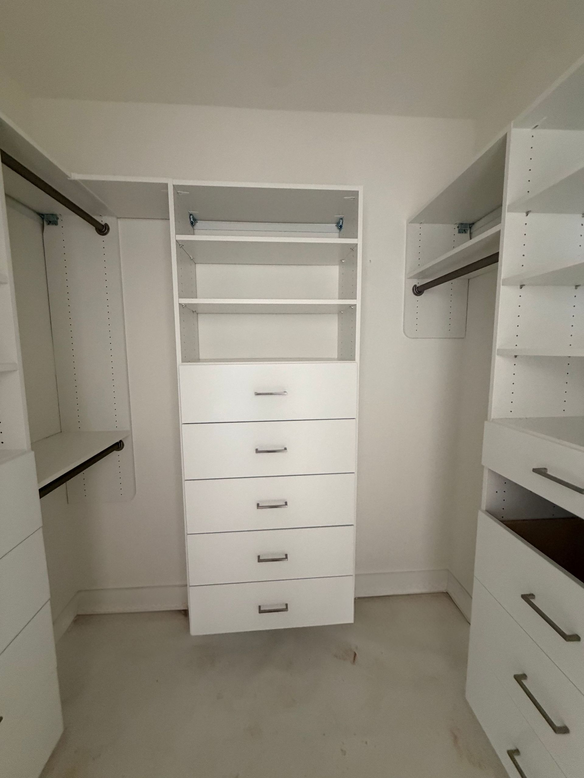Walk-in closet with white built-in shelves, drawers, and hanging rods