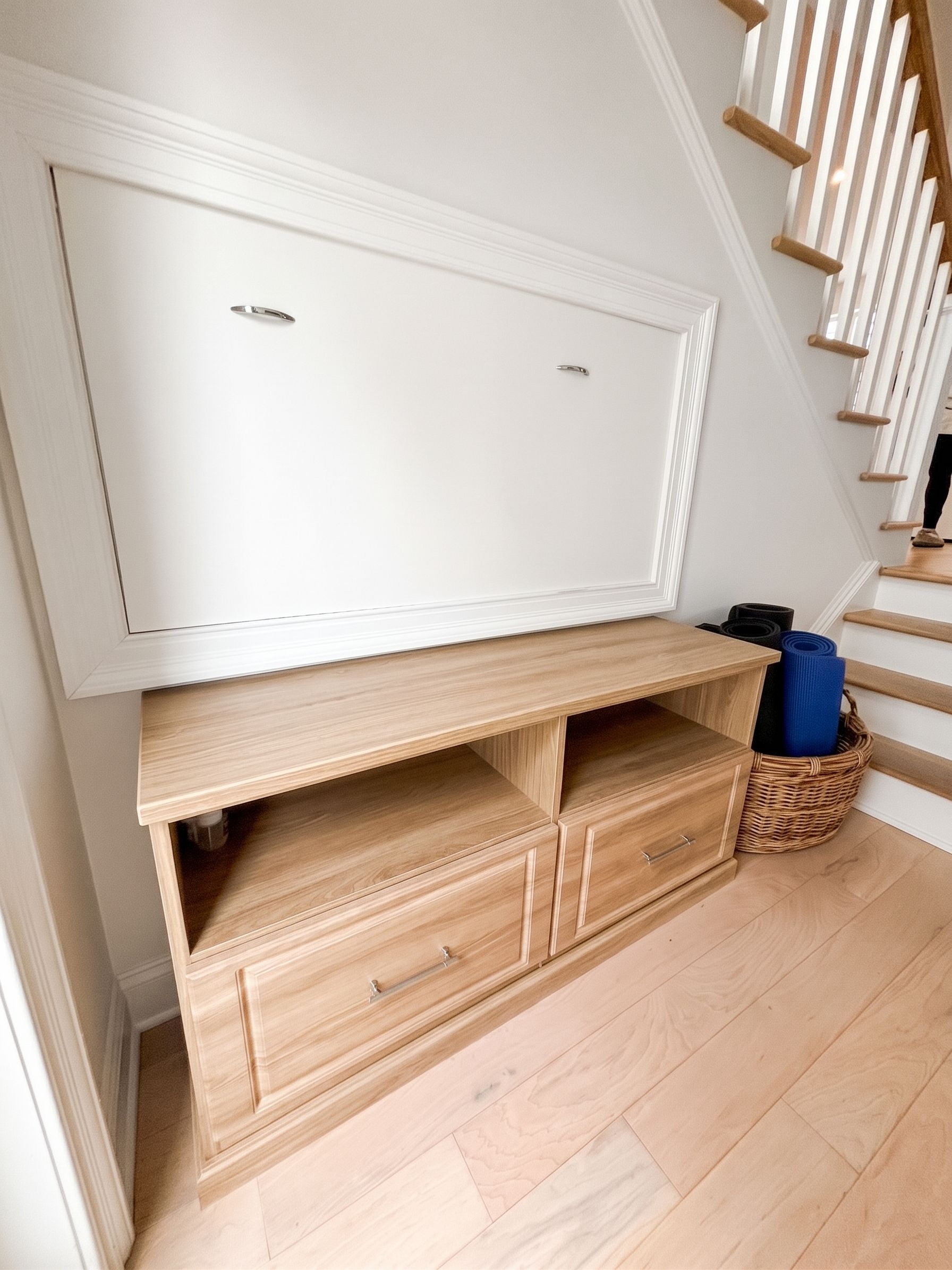 Wicker shoe cabinet with lift-up top and drawers in a bright entryway beside stairs