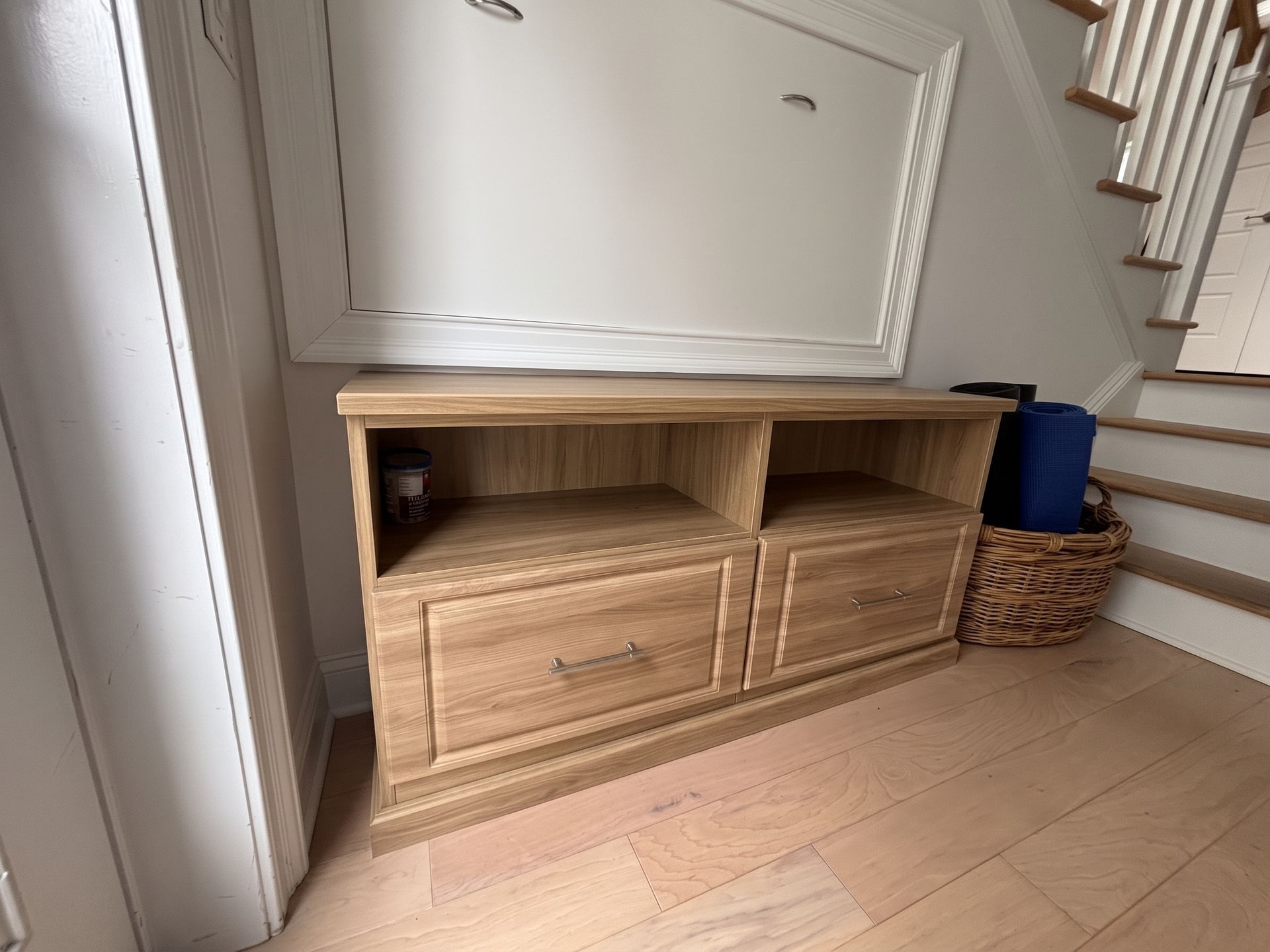 mudroom with storage drawers in a hallway beside stairs and woven baskets