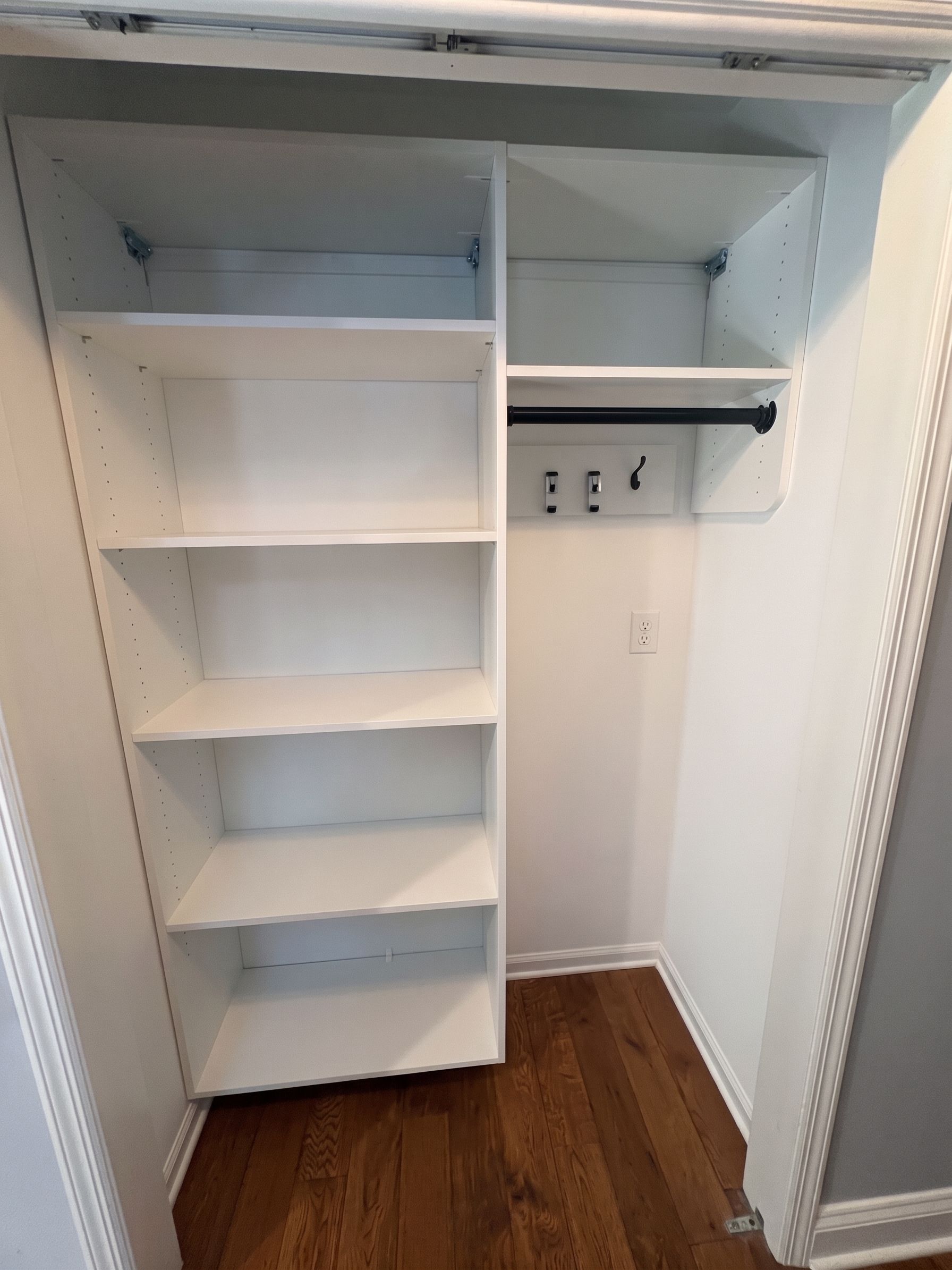 White reach-in closet with built-in shelves, hanging rod, and wood floor