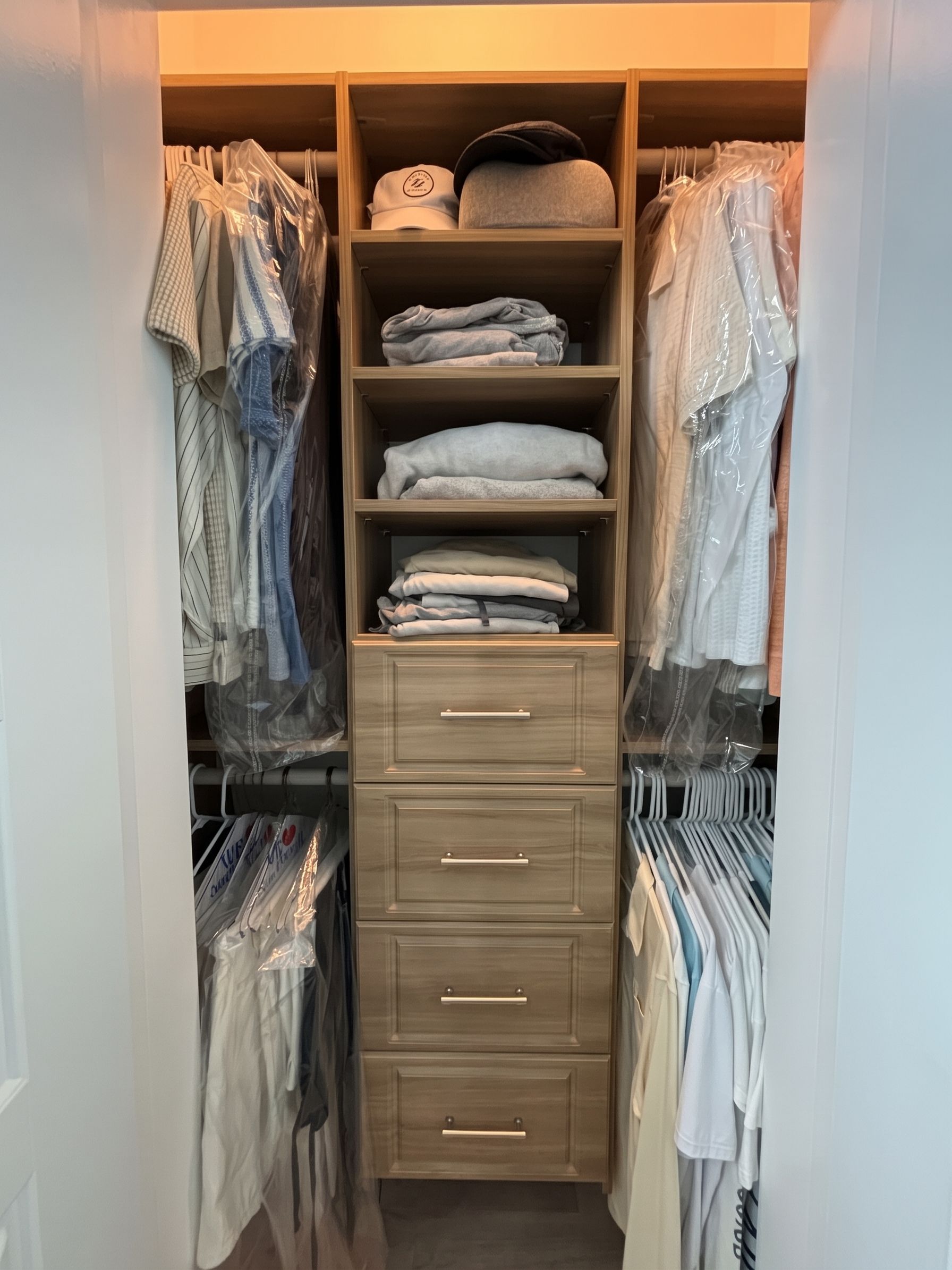 Reach in closets with hanging clothes, folded linens, and a central wooden drawer unit
