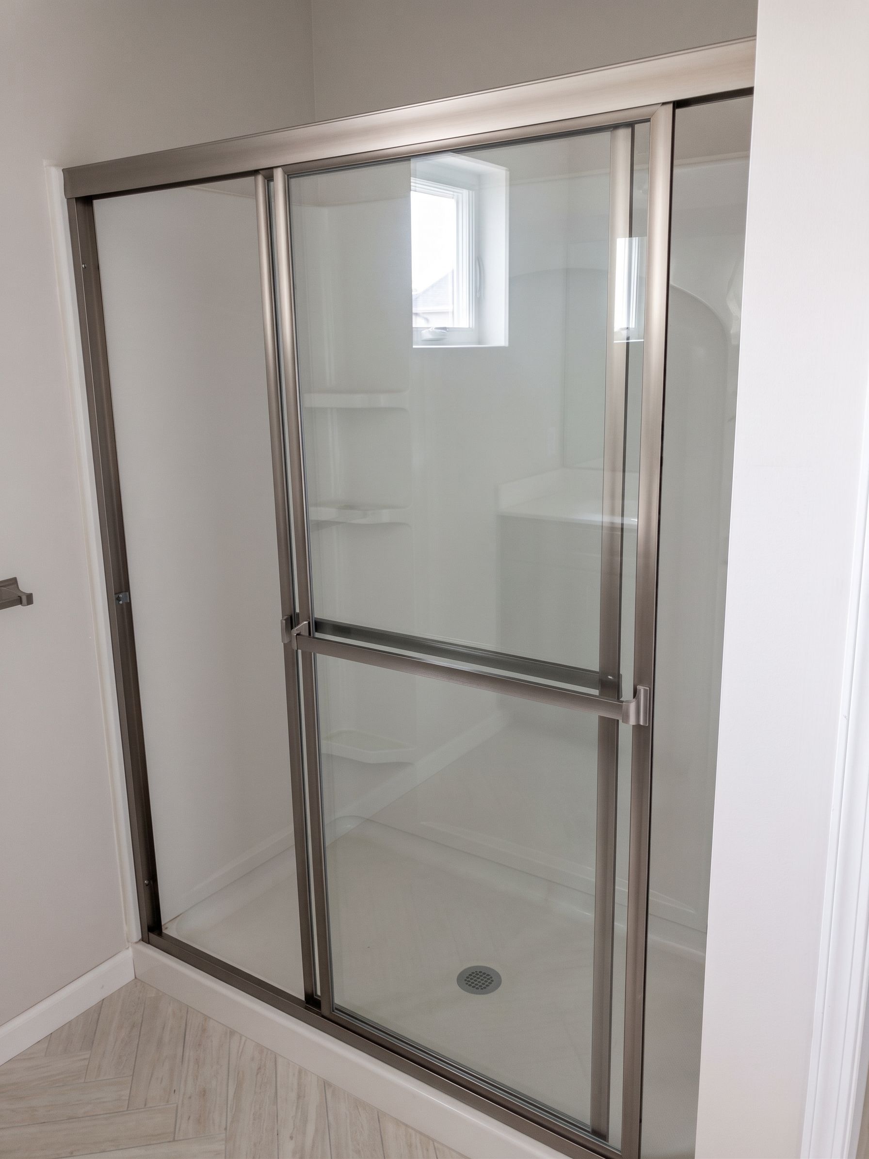 Glass shower enclosure with chrome trim in a white bathroom