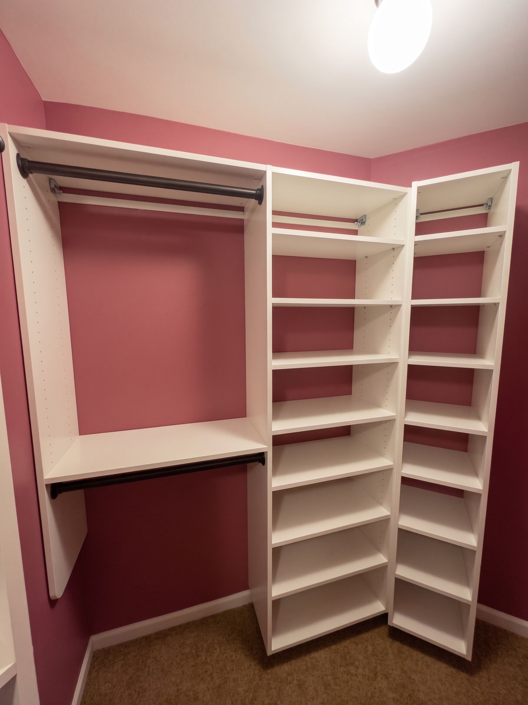 Empty pink walk-in closet with white shelves, hanging rods, and built-in storage units