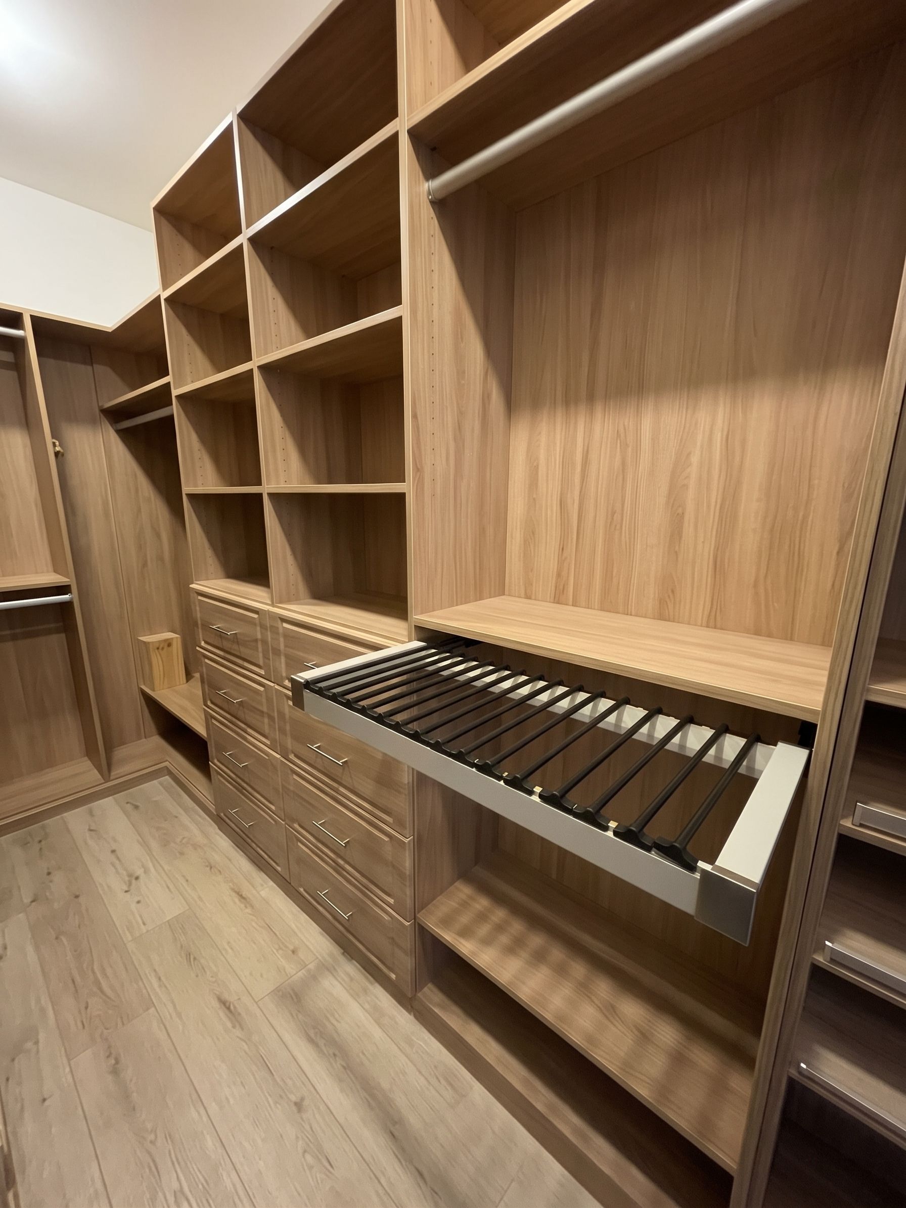 Walk-in closet with wood shelving, drawers, and a pull-out pants rack