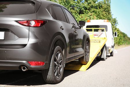 White Tilt Tray Truck Towing Black Car — Tyre Service in Springsure, QLD