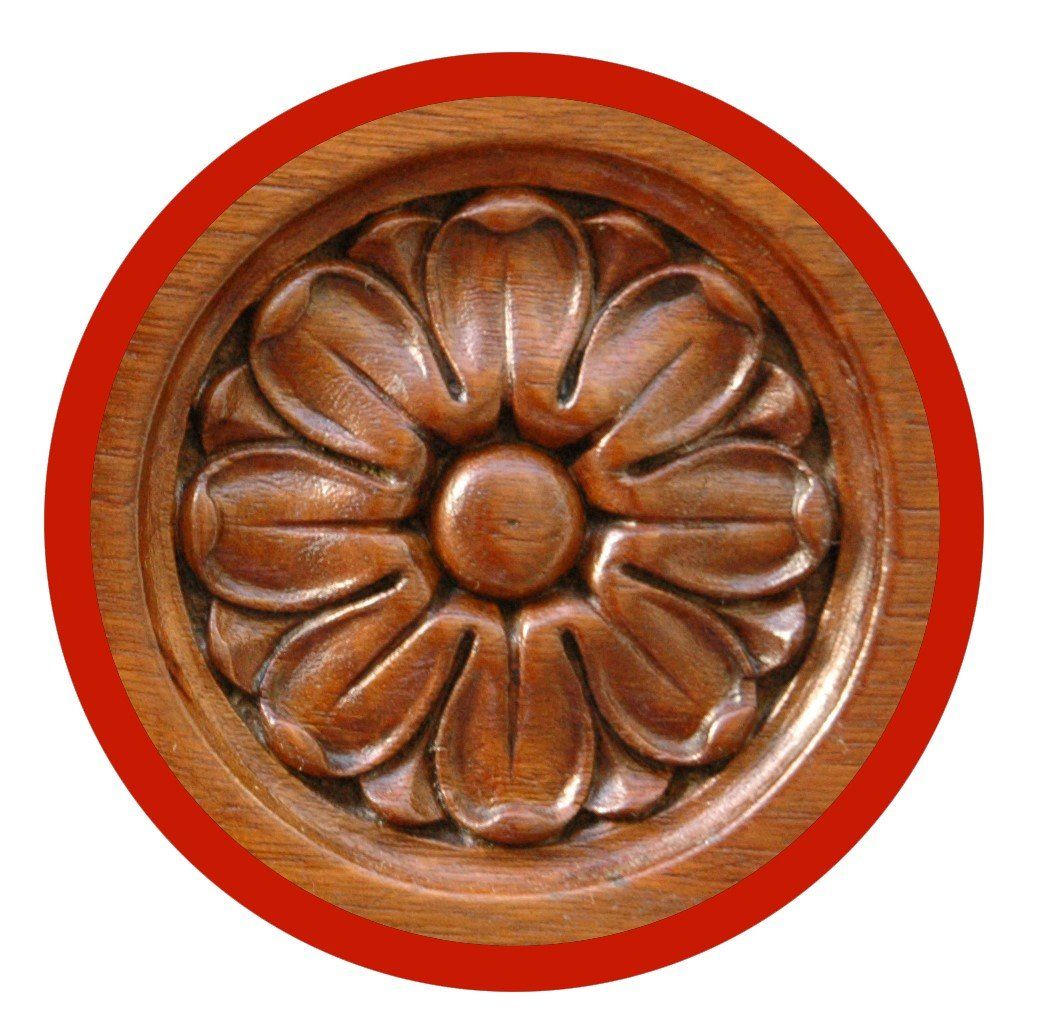 Intaglio rotondo in legno a forma di rosetta raffigurante un fiore stilizzato e simmetrico a otto petali con un bocciolo centrale.