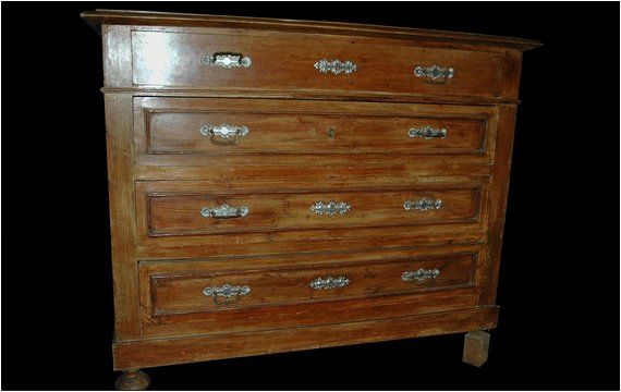 Cassettiera in legno con quattro cassetti e maniglie decorative in metallo su sfondo nero.