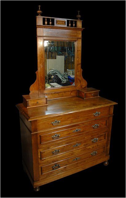 Cassettiera in legno in stile vittoriano con quattro cassetti, due piccoli armadietti laterali e uno specchio alto con un coperchio decorativo.