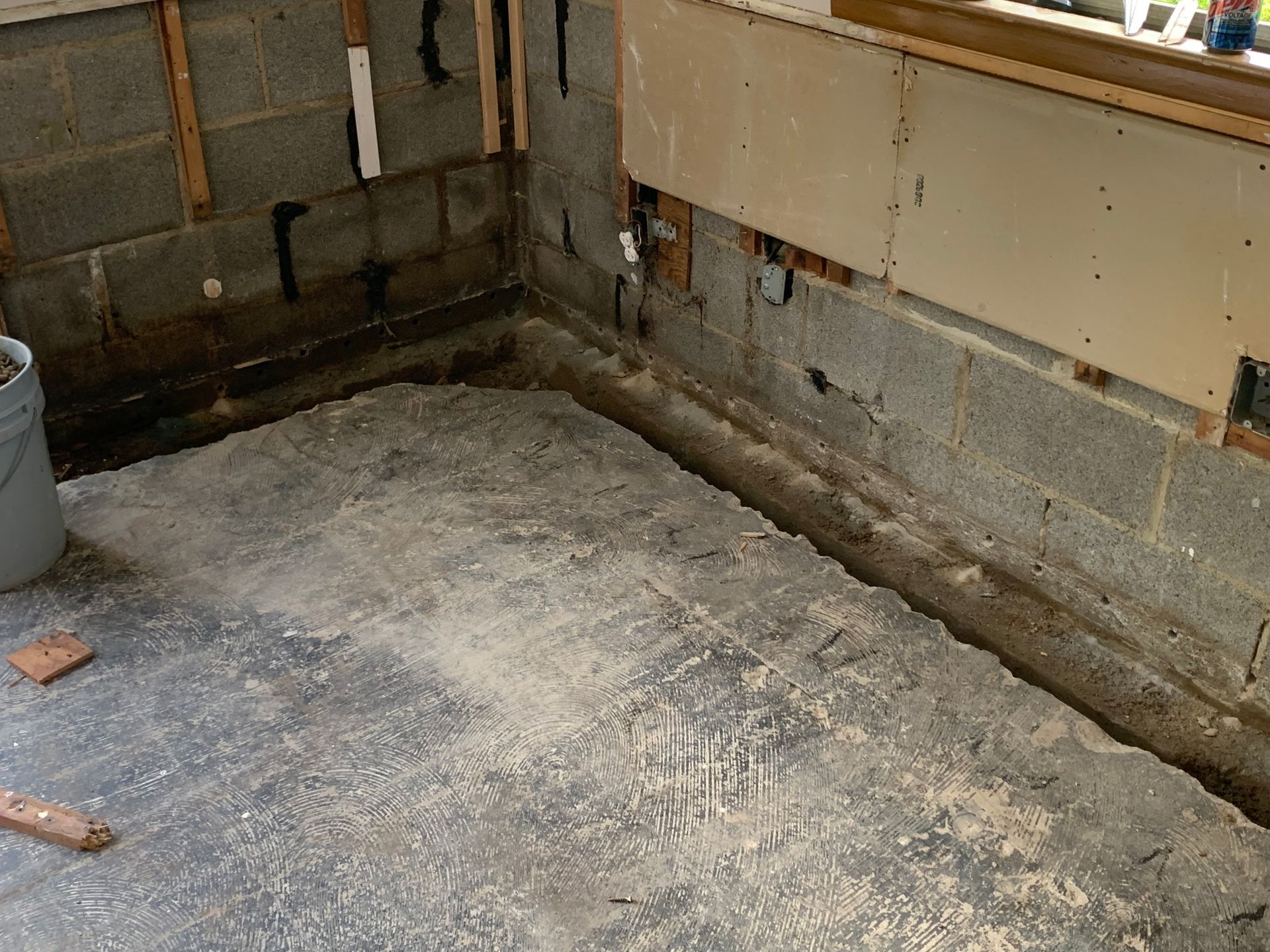 Empty concrete basement corner with unfinished walls and floor, showing exposed pipes and utility area