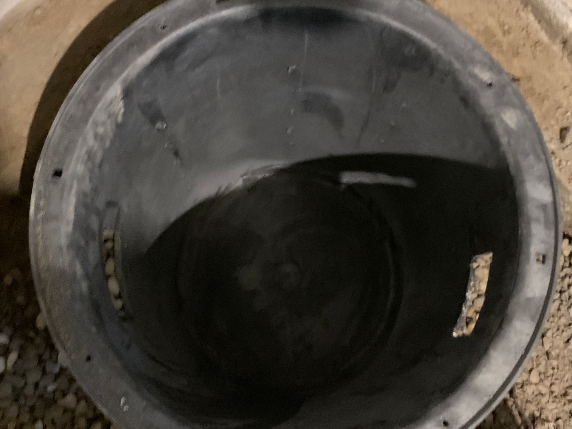 Black plastic bucket or bin viewed from above on a concrete surface