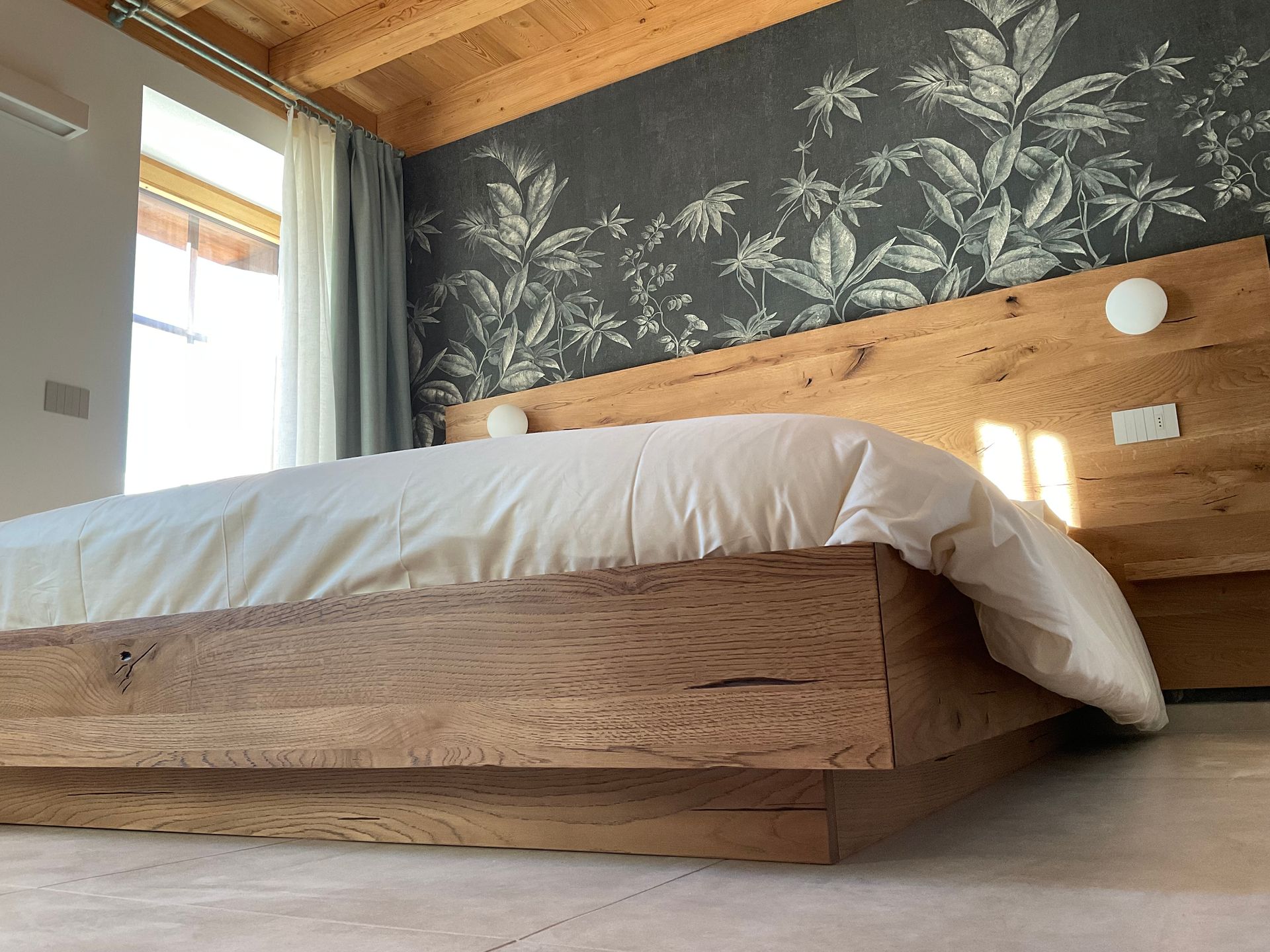 Una camera da letto con un letto in legno e una carta da parati floreale sulla parete.