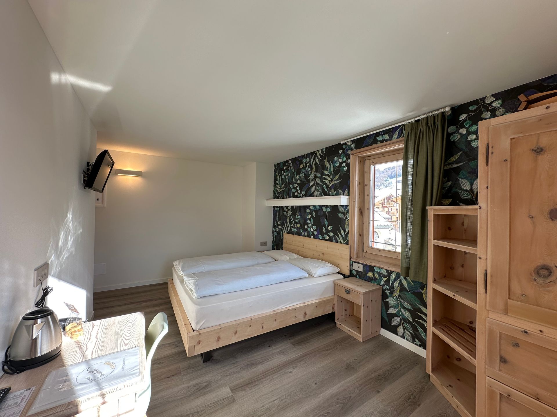 Camera da letto con letto matrimoniale, mobili in legno e carta da parati a motivi.