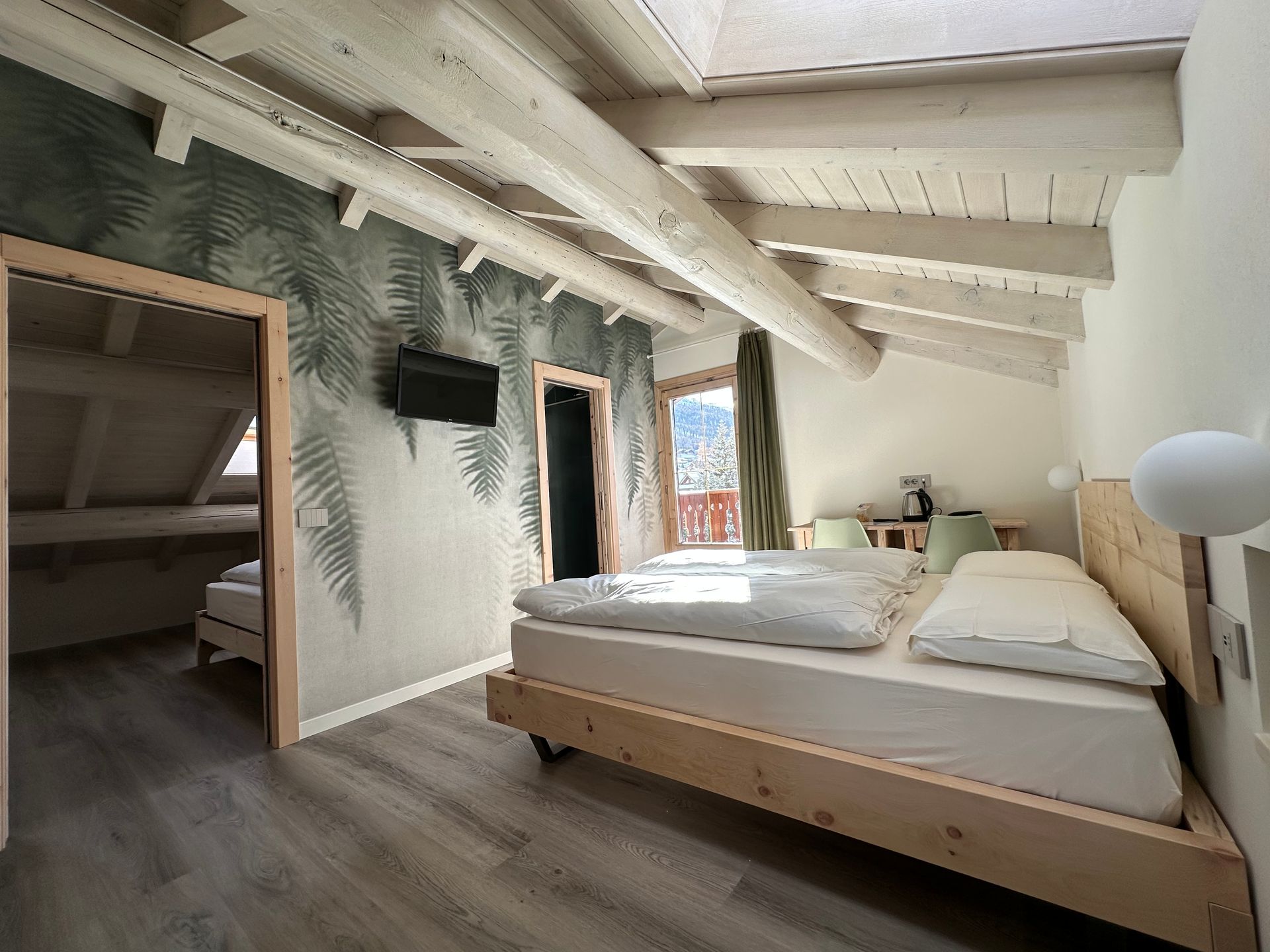 Una camera da letto con due letti e una televisione a parete.