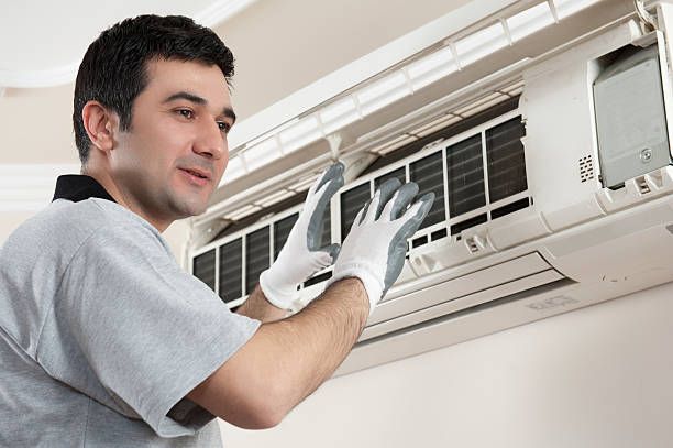 A technician smiles while performing a professional air conditioning install at a client’s home.