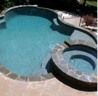 Swimming pool with attached hot tub, edged with stone; turquoise water; stone patio.