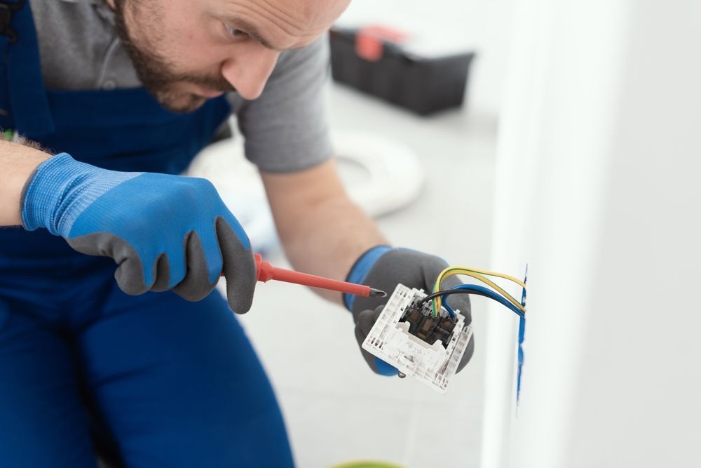 A man is fixing a light switch with a screwdriver.
