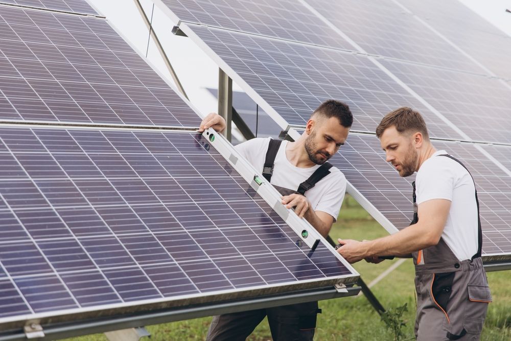 Two men are working on a solar panel in a field.