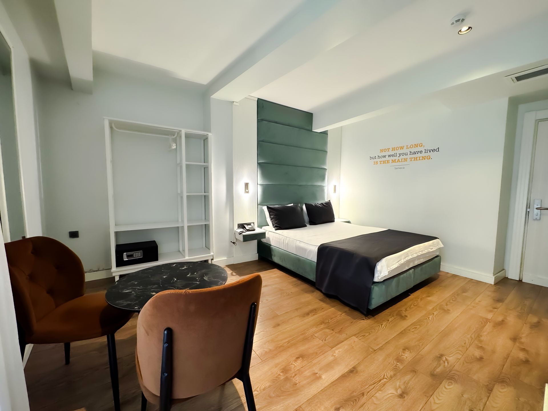 Modern bedroom with a large bed, wood floors, two chairs, and a wall-mounted TV cabinet